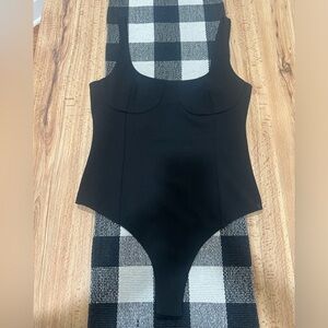 Tight fitting black bodysuit with shape outline detail throughout
